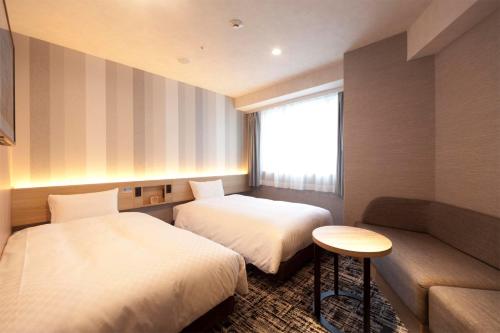 a hotel room with two beds and a couch at Kumamoto Washington Hotel Plaza in Kumamoto