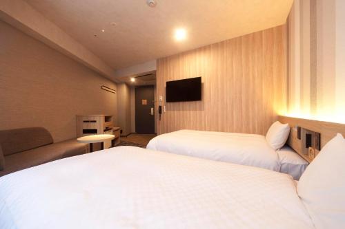 a hotel room with two beds and a flat screen tv at Kumamoto Washington Hotel Plaza in Kumamoto