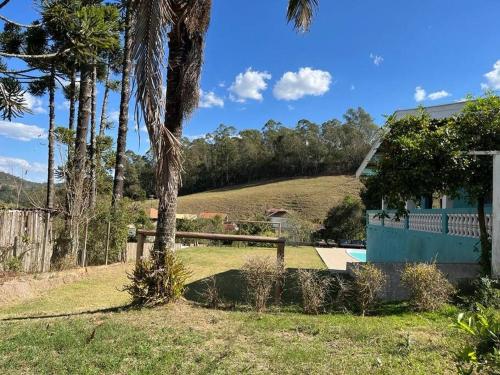 a house with a yard with a fence and palm trees at Recanto do sossego in São Bento do Sapucaí