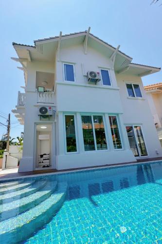 a villa with a swimming pool in front of a house at 芭提雅海边梦幻民宿 in Jomtien Beach