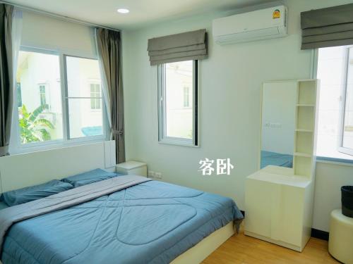 a bedroom with a blue bed and two windows at 芭提雅海边梦幻民宿 in Jomtien Beach