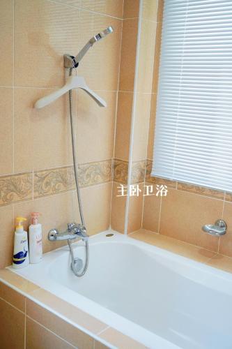 a bath tub with a shower head in a bathroom at 芭提雅海边梦幻民宿 in Jomtien Beach