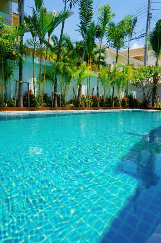 a swimming pool with blue water and palm trees at 芭提雅海边梦幻民宿 in Jomtien Beach