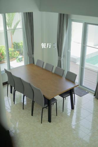 a wooden table and chairs in a room with windows at 芭提雅海边梦幻民宿 in Jomtien Beach