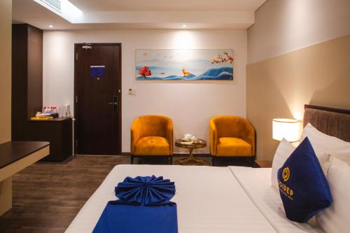 a hotel room with a bed and two chairs at SANDALS AQUILA HOTEL in Bao Loc