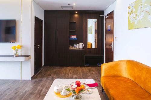 a living room with a table and a yellow couch at SANDALS AQUILA HOTEL in Bao Loc