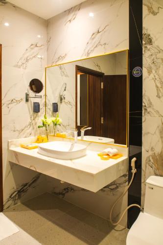 a bathroom with a sink and a large mirror at SANDALS AQUILA HOTEL in Bao Loc