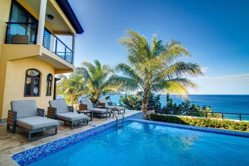 a house with a swimming pool next to the ocean at Oceanfront Luxe Villa In St Mary Fully Staffed in St Mary