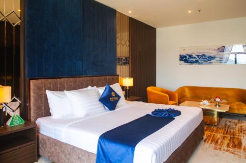 a hotel room with a large bed and a chair at SANDALS AQUILA HOTEL in Bao Loc
