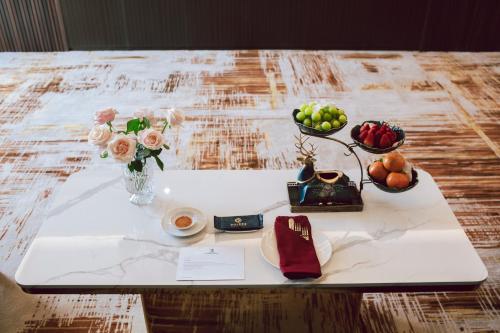 a white table with bowls of fruit and flowers on it at SANDALS AQUILA HOTEL in Bao Loc