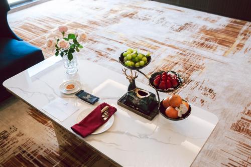 a table with bowls of fruit and a vase of flowers at SANDALS AQUILA HOTEL in Bao Loc