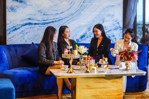 a group of women sitting around a table with cakes at SANDALS AQUILA HOTEL in Bao Loc