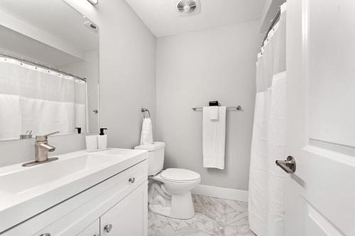 Baño blanco con aseo y lavamanos en Cozy 2 Bedroom Stay in Rochester Hills, en Rochester Hills