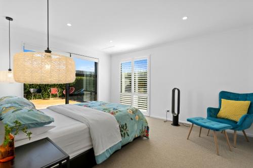 een slaapkamer met een bed en een blauwe stoel bij House Naomi - Martinborough Holiday Home in Martinborough 