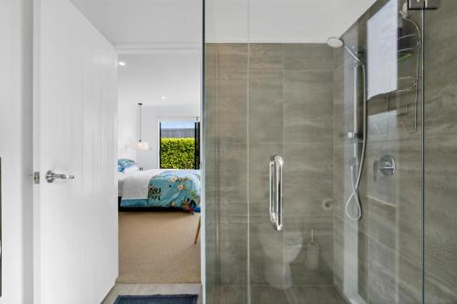 een badkamer met een douche en een slaapkamer met een bed bij House Naomi - Martinborough Holiday Home in Martinborough 