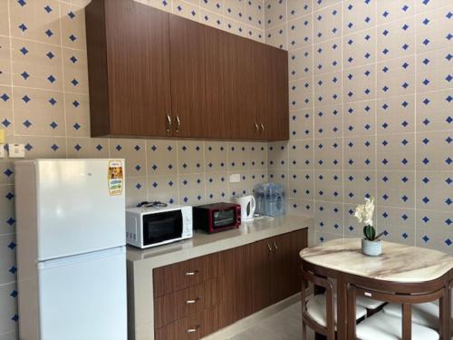 a kitchen with a refrigerator and a table with a microwave at A'yn Homestay in Bandar Seri Begawan