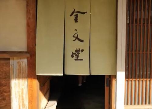 eine Tür mit asiatischem Schreiben an der Seite eines Gebäudes in der Unterkunft 金文堂　kinbundo in Ao