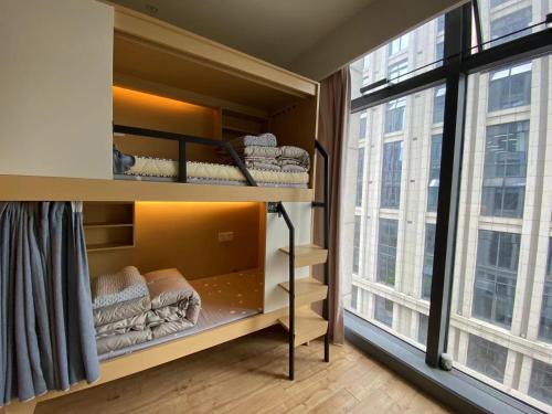 a room with bunk beds with a large window at Hangzhou inn Time Youth Hostel in Hangzhou