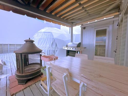 富士河口湖的住宿－Necoana Glamping Annovillasグランピング，甲板上的木桌和燃木火炉