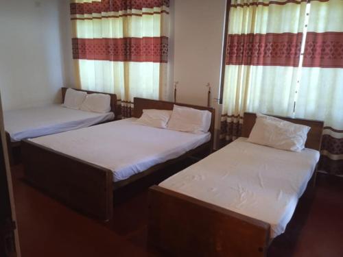 two twin beds in a room with windows at RS Holiday Residence in Ilukkumbura