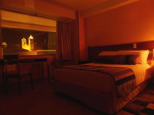 a bedroom with a bed and a desk and a window at Hotel Estación Sabana in Zipaquirá