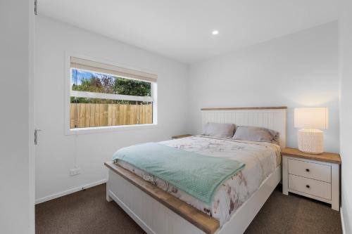 a white bedroom with a bed and a window at Close to Town & Lake - Taupo in Taupo