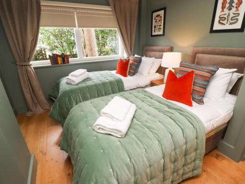 2 łóżka w pokoju z zielonymi i pomarańczowymi poduszkami w obiekcie Tidal Waters w mieście Plymouth