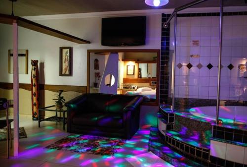 Bali Motel (Adults Only) في فورتاليزا: غرفة معيشة مع حوض استحمام وأريكة