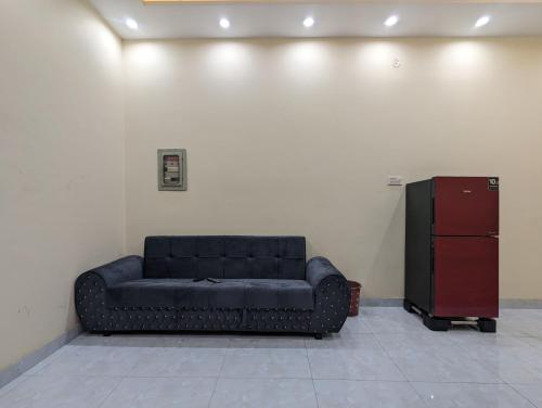 a black couch in a room with a refrigerator at Central Residence in Gujrānwāla