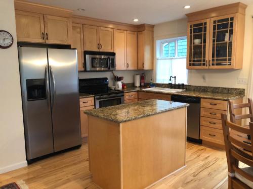 a kitchen with a stainless steel refrigerator and wooden cabinets at Seagrass Cottage at Beverly Beach in Newport
