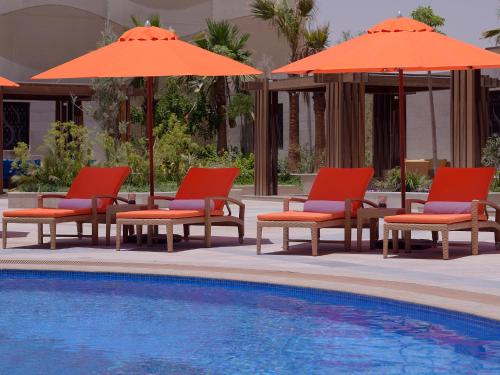 a group of chairs and umbrellas next to a pool at Voco - Riyadh by IHG in Riyadh