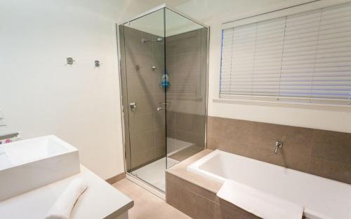 y baño con ducha, lavabo y bañera. en Point Lonsdale Holiday Apartments, en Queenscliff