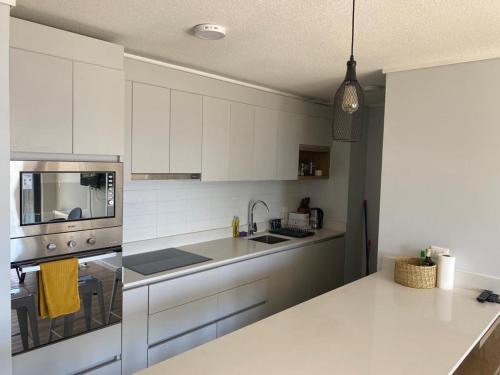 una cocina con armarios blancos y un aparato de acero inoxidable en Agradable depa en Llanquihue, en Llanquihue