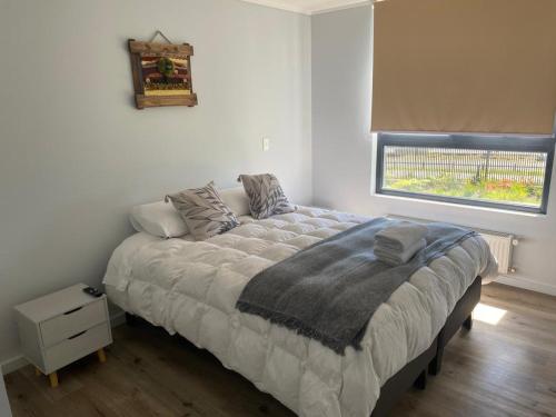 1 dormitorio con 1 cama grande y ventana en Agradable depa en Llanquihue, en Llanquihue