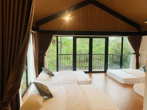 Habitación con 2 camas y ventana grande. en Đinh Gia Home Villa & Resort, en Ninh Binh
