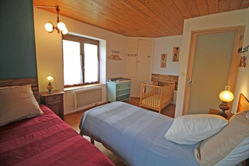 1 dormitorio con 2 camas, ventana y cuna en Le vieil orme en Saint-Junien