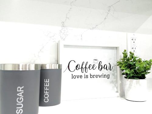 a coffee bar love is brewing mug next to a plant at Urban Haven: 2BR/2BA+Office, Kitchen, Dining in Newcastle