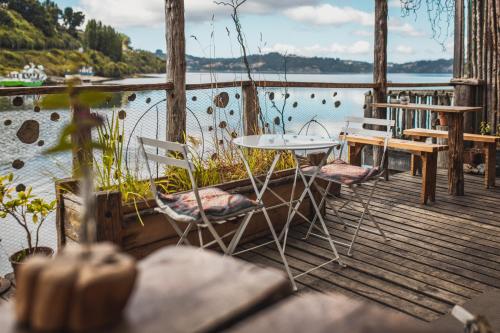 a table and chairs on a dock with a body of water at Palafito Hostel Chiloé in Castro