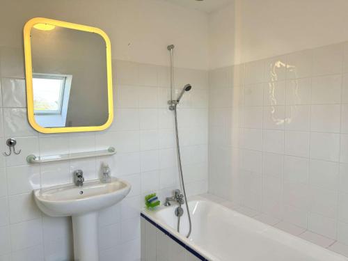 une salle de bain avec un lavabo, une baignoire et un miroir dans l'établissement Maison coquette proche plage à La Forêt-Fouesnant - FR-1-481-159, à La Forêt-Fouesnant