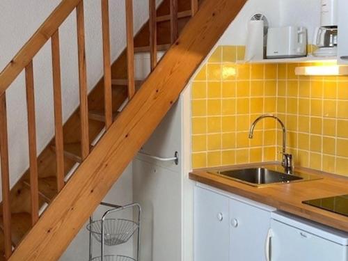 una cocina con azulejos amarillos y una escalera de madera en Appartement Saint-Martin-de-Ré, 2 pièces, 4 personnes - FR-1-544-26, en Saint-Martin-de-Ré