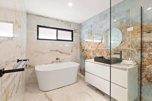 een badkamer met een bad, een wastafel en een spiegel bij CASSA CHEVRON ISLAND- Luxury Waterfront House in Gold Coast