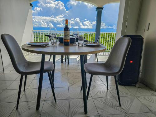 stół z butelką wina i 2 krzesłami w obiekcie Maison (Vu sur le Lagon) w mieście Le Gosier
