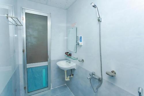 uma casa de banho branca com um lavatório e um chuveiro em Motel Tulip em Da Nang