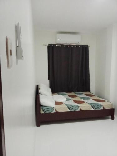 uma pequena cama num quarto com uma cortina em Melona's Villa em Tagbilaran