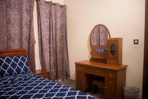 a bedroom with a bed and a dresser and a mirror at Kadoued Furnished Apartment 2 Bedroom in Ouagadougou