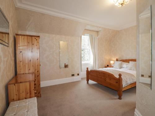 a bedroom with a wooden bed and a window at Arden House in Kingussie