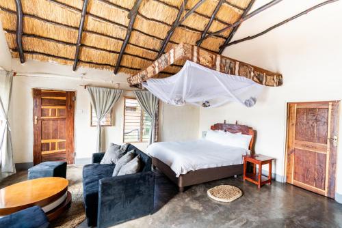 1 dormitorio con cama, sofá y mesa en Njobvu Safari, en Kakumbi