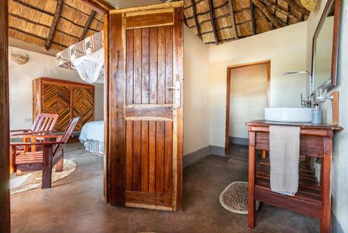 baño con lavabo y puerta de madera en Njobvu Safari, en Kakumbi