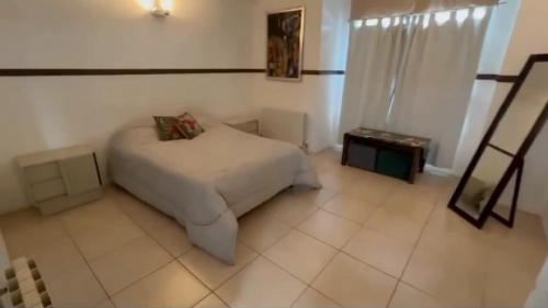 um quarto com uma cama branca e uma janela em Wonderful house em Puerto Madryn