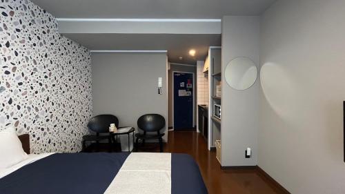 a bedroom with a bed and two black chairs at Stay Airport in Fukuoka